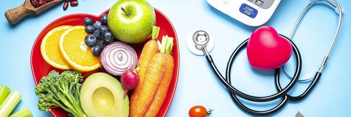 Plate of fruits and vegetables next to a stethoscope 