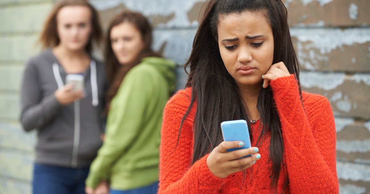 A young teen looks at her phone sadly