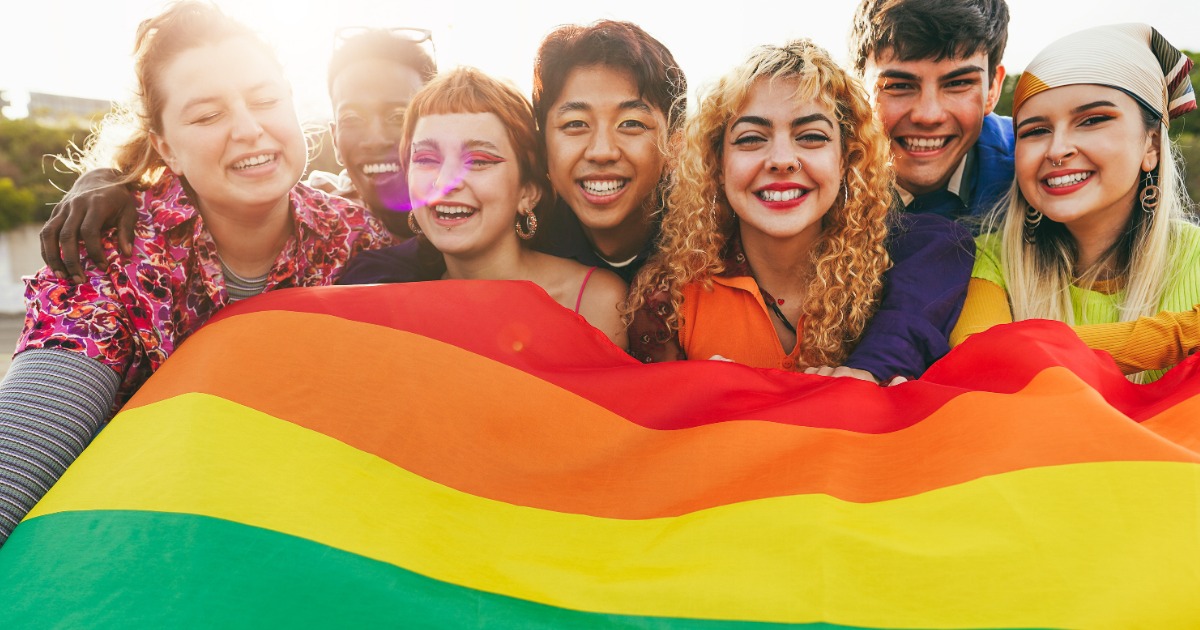 A group of friends hold a pride flag