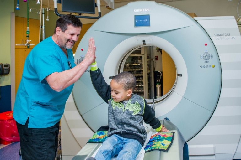 physician and child giving each other a high five after MRI scan