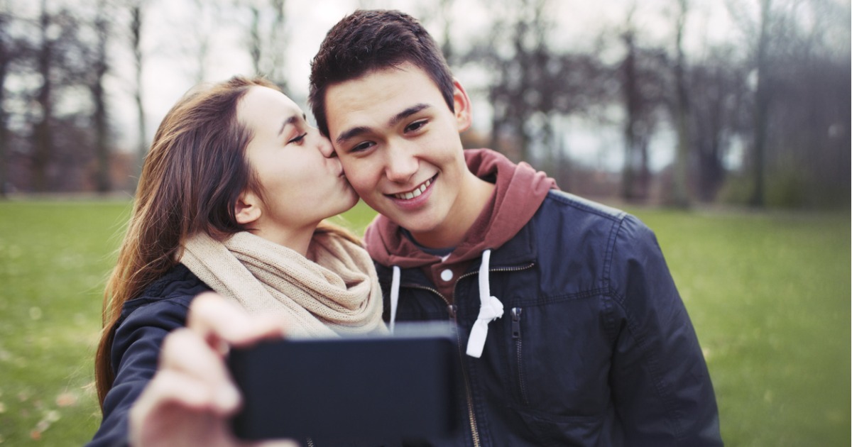 A girl kissing her boyfriend on the cheek