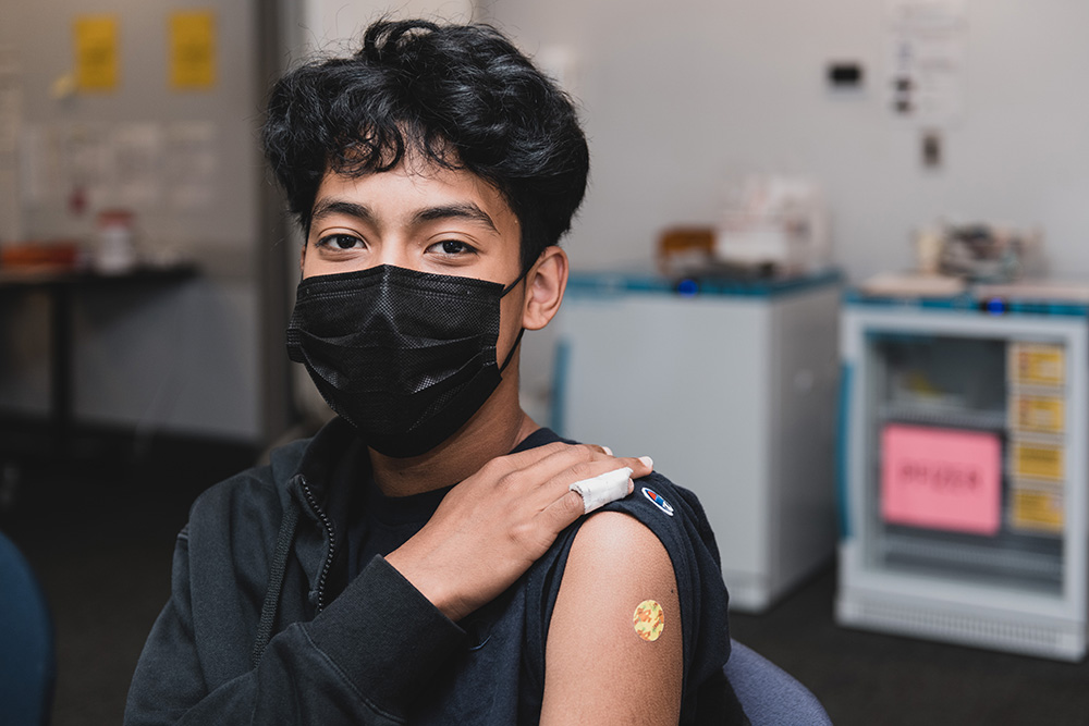 A teen shows off where they got their COVID vaccine