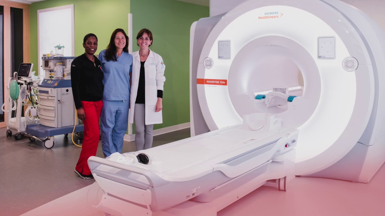 Cardiology fellow and cardiology team members stand beside the 3T MRI scanner