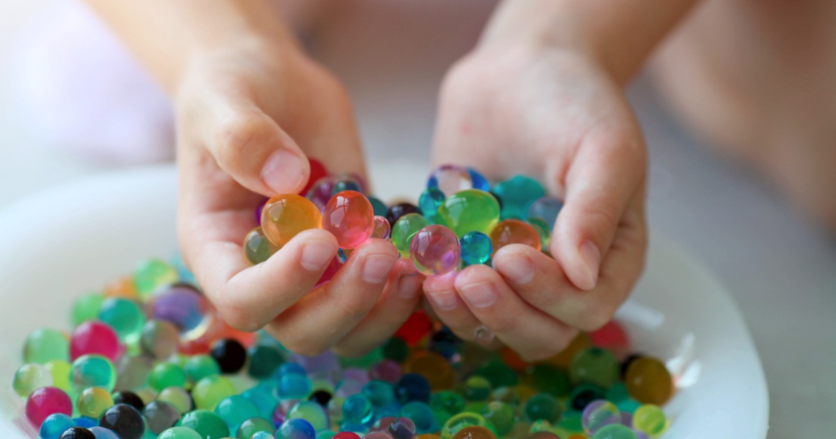 Water beads in hand over bowl. Dangerous toy.