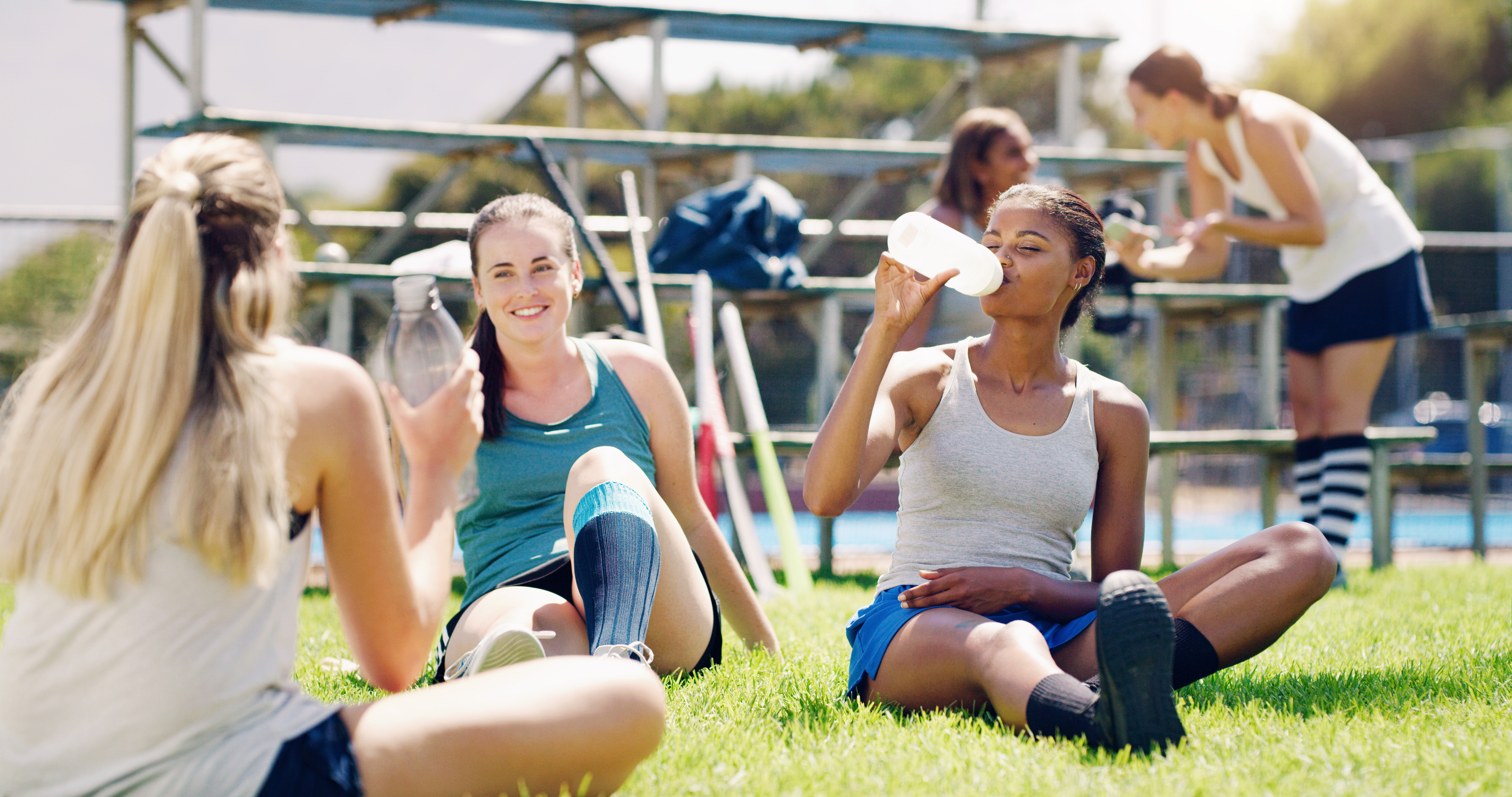 Group of teen female athletes drinking water on field