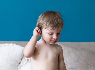 Toddler boy rubs right ear with hand