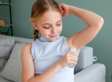 Preteen girl applying deodorant