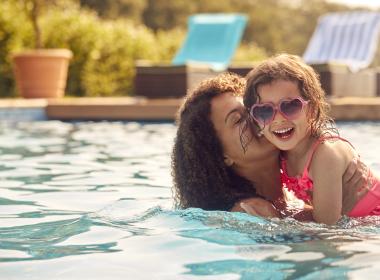 Mom and young daughter swimming in pool. Mom holding daughter.