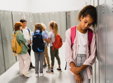 Preteen girl leaning against locker, not thrilled