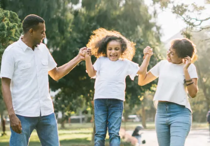 Girl swinging in-between Mom and Dad's hands