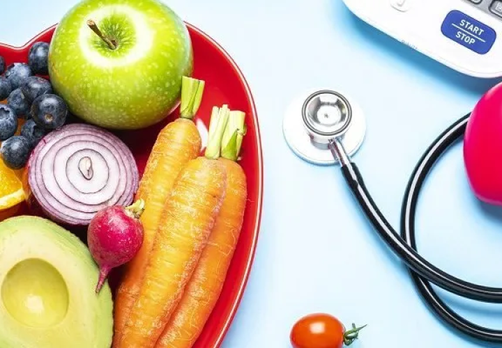 Plate of fruits and vegetables next to a stethoscope 