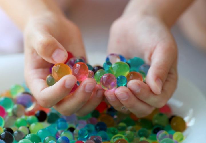 Water beads in hand over bowl. Dangerous toy.