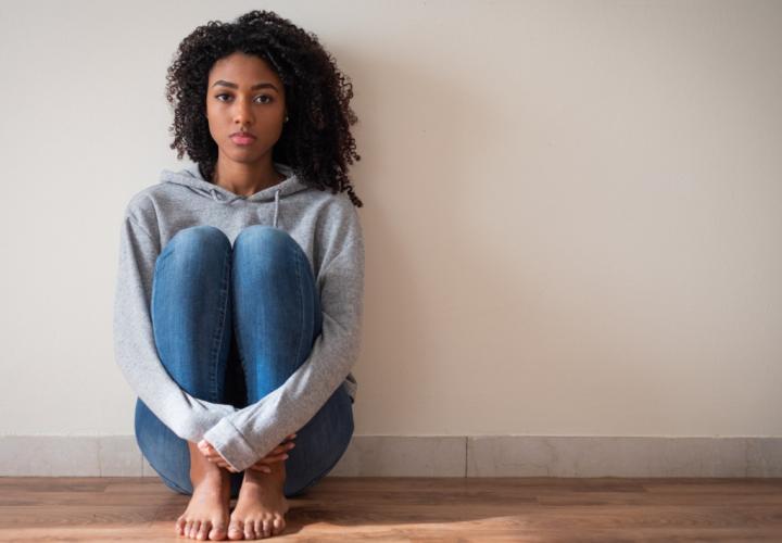 Young girl sits on floor, feeling sad and depressed.