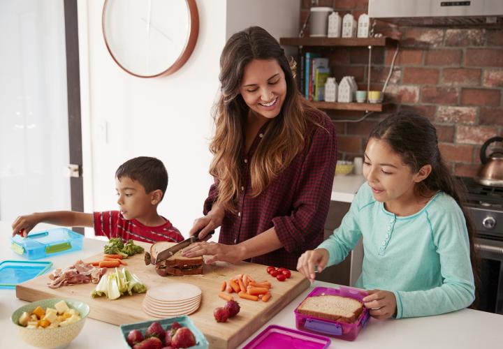 Mom with two school-aged kids in kitchen food prepping