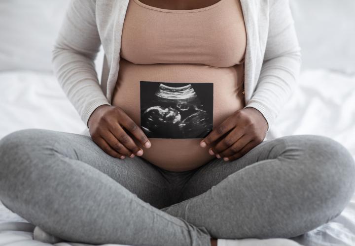 Black Woman holding sonogram. 