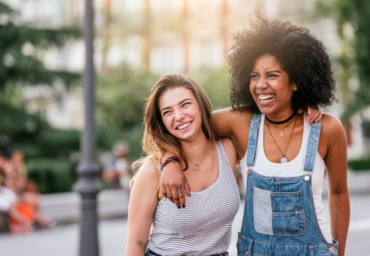 Teenage females smiling, in street. Motivate your teen this summer.