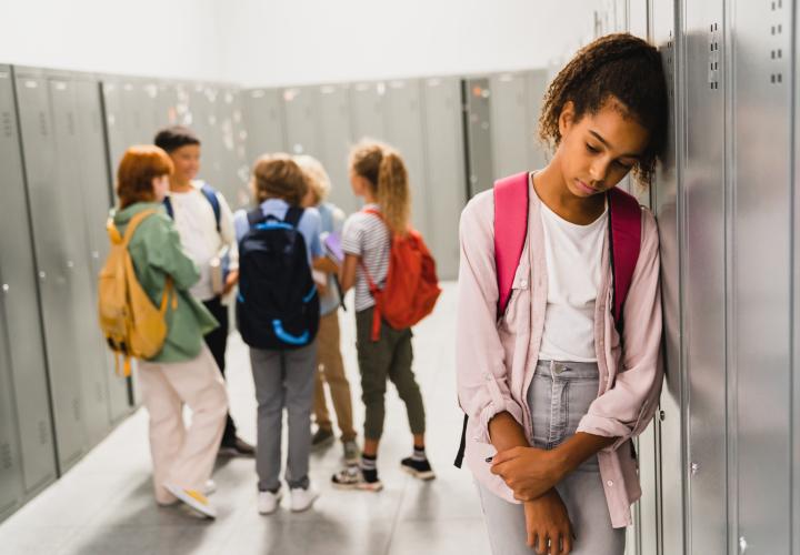 Preteen girl leaning against locker, not thrilled