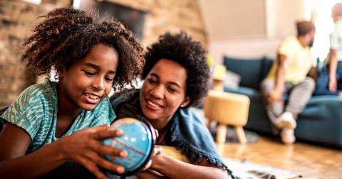 A mother and daughter look at a globe