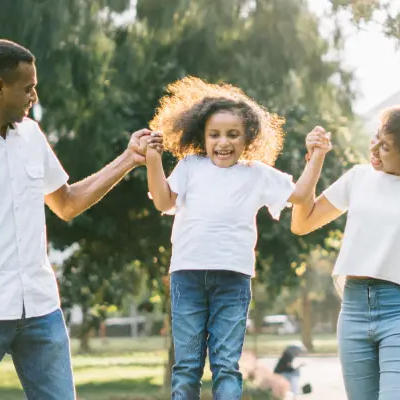 Girl swinging in-between Mom and Dad's hands