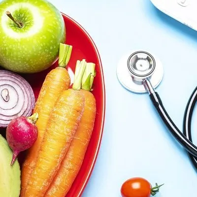 Plate of fruits and vegetables next to a stethoscope 