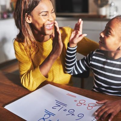 Mom and school-aged daughter high-fiving during math assignment