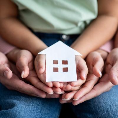 Hands holding a paper cutout of a house.