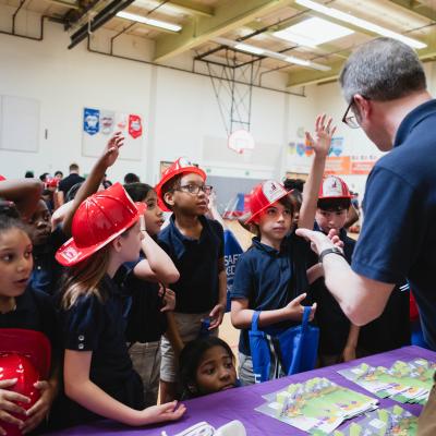 School-aged kids holding red safety hats at gun safety conference